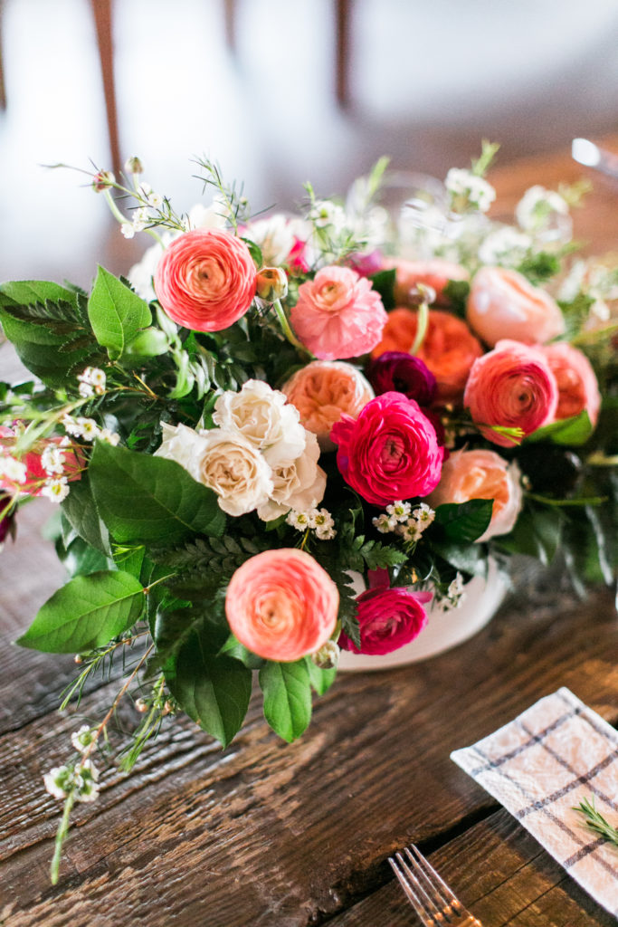 bright coral floral centerpieces on wooden table