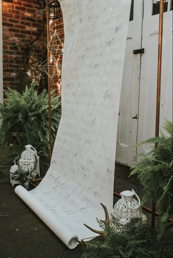 ceremony backdrop with vows written on scroll and ferms