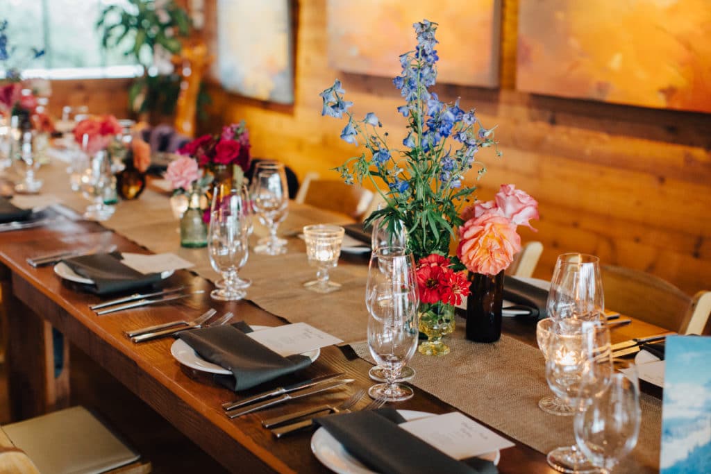 family style wedding tables with bright florals and black napkins