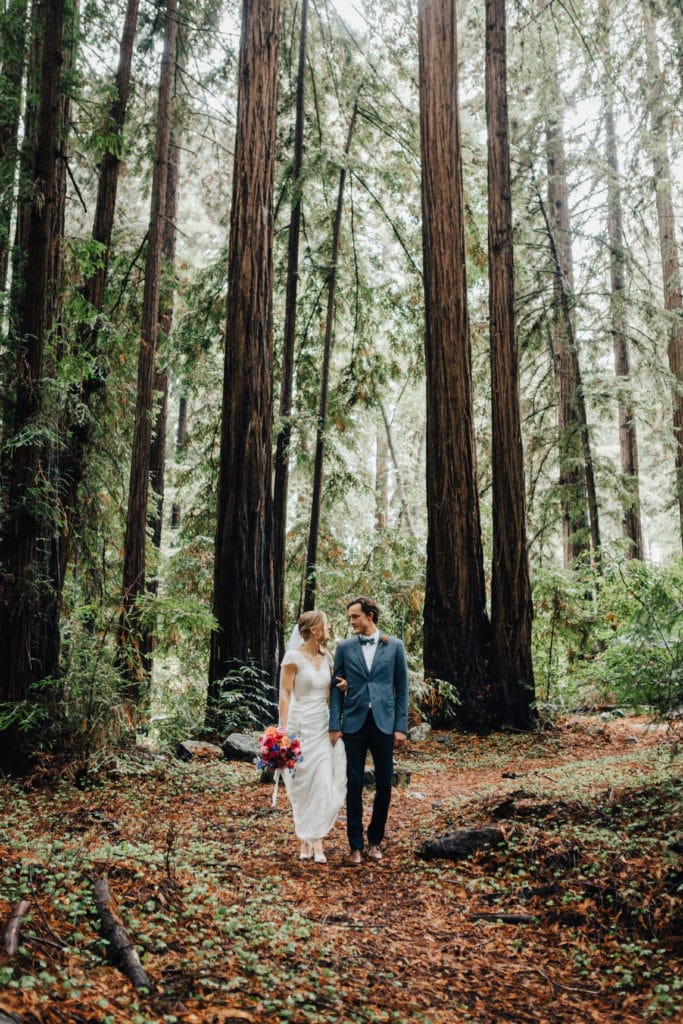 couple walks through woods for wedding big sur