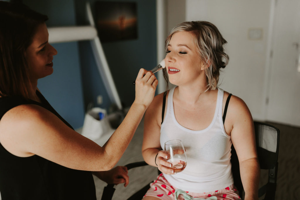 Bride getting ready with blonde updo and glass of rose for a Laguna Beach Elopement