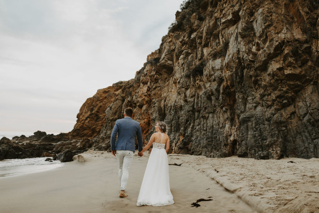 Bride and groom walk along the beach in Laguna Beach, CA after small elopement ceremony