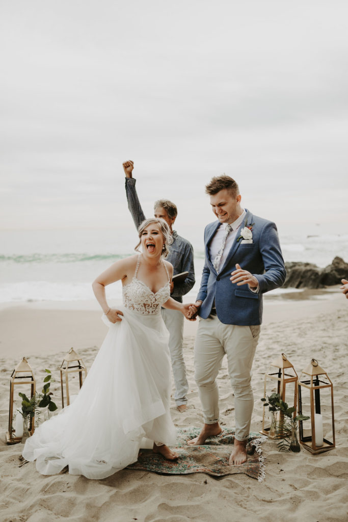 Bride and groom celebrate after getting married on the beach in Laguna Beach California