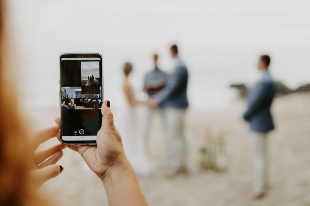 Skyping in the bride and groom's family on a phone during a surprise elopement on the beach in Laguna Beach California