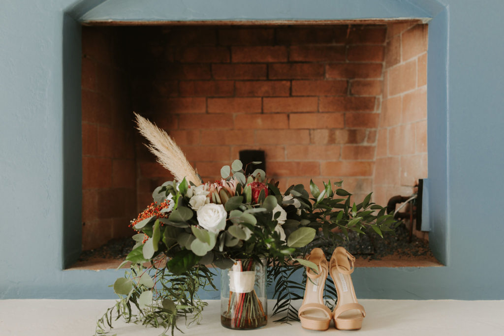 Wild boho bouquet with king protea and pampass grass and nude wedding shoes