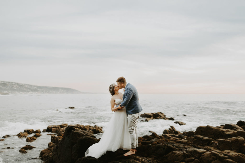 Bride and groom kiss on rocky cliff in Laguna Beach Elopement