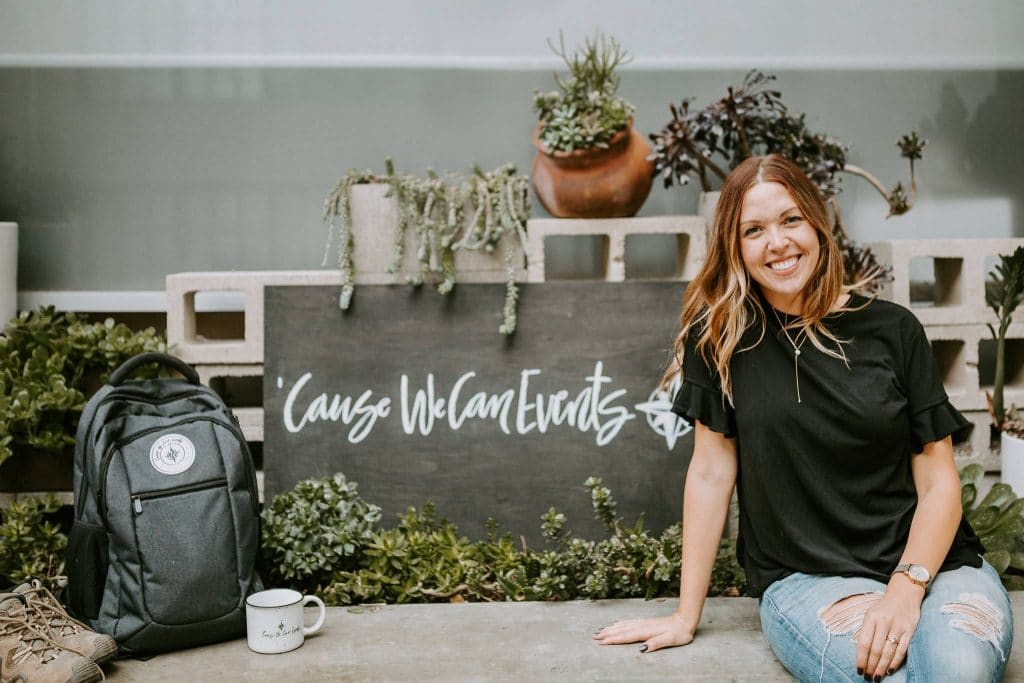 Event Planner, Gabby Pinkerton of Cause We Can Events with branded mug and logo on wooden sign. Succulent garden with concrete walls for lifestyle shoot in Long Beach, CA