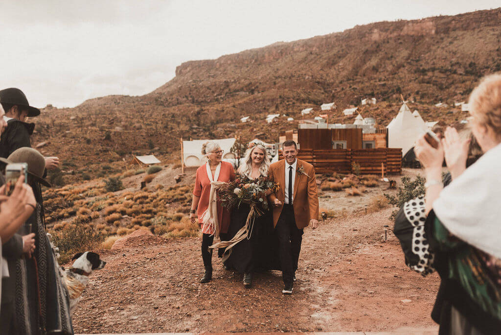 Bride in all black walks down rainy aisle at Under Canvas Zion