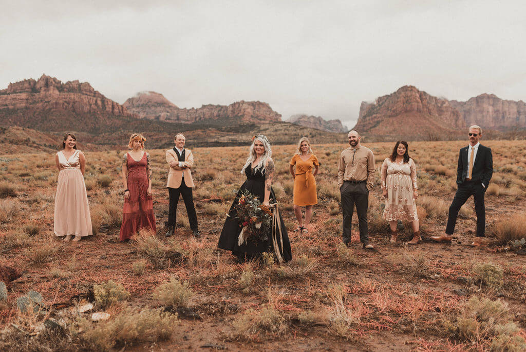 Bride in black wedding dress and her tribe out in the desert. Zion Under Canvas Wedding.