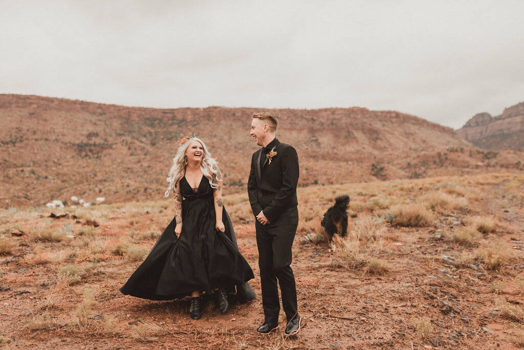 Bride and groom in all black in desert at Zion Under Canvas. First look with the desert behind them before their epic glamping wedding,